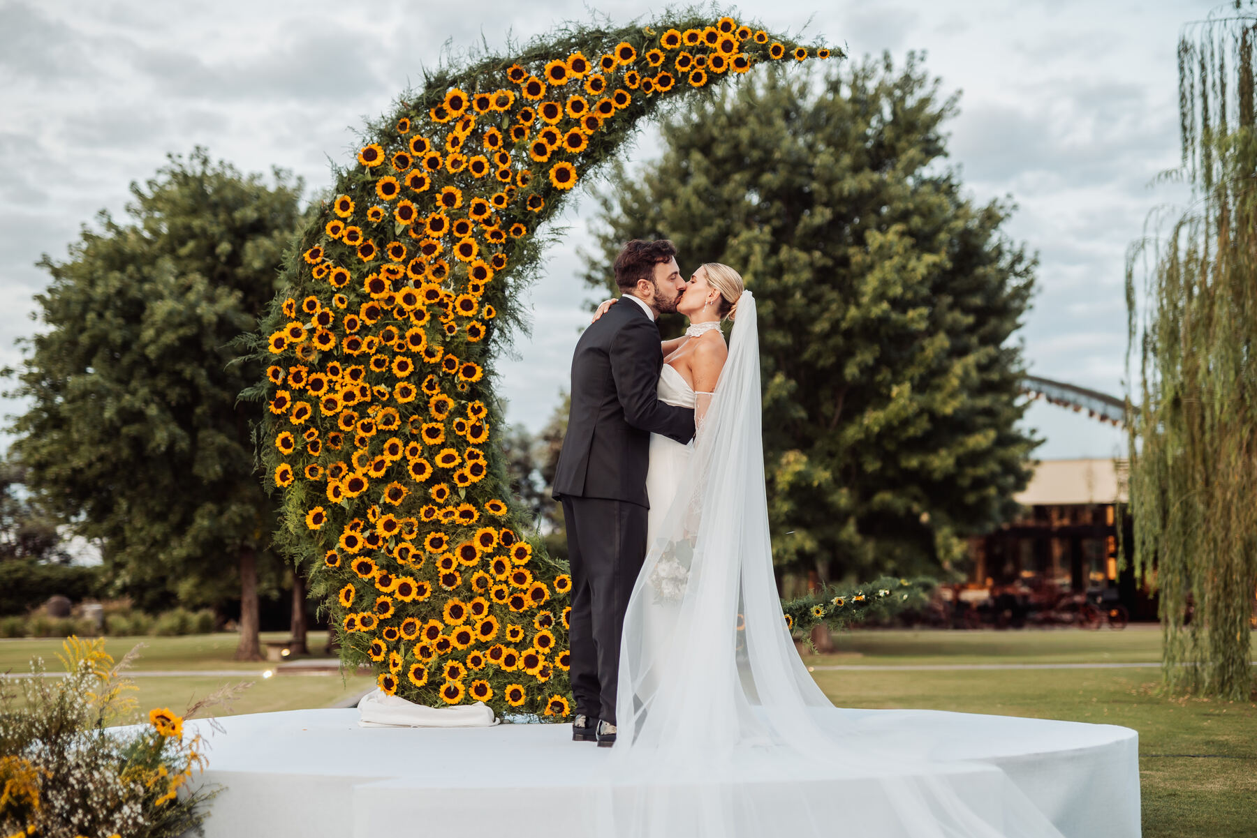 Sofi y Martín besándose frente a la luna de girasoles